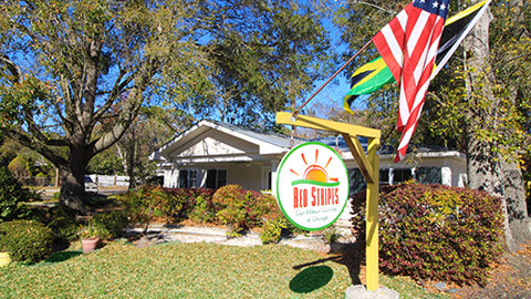 Red Stripes Caribbean Cuisine. a sign that says Red Stripes in front of a house