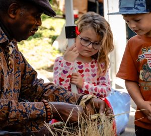The Historic Bluffton Arts & Seafood Festival. man showing a little girl and boy basket weaving