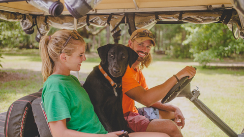 Golf Carting Your Way Through Bluffton. a man, girl and black lab in what appears to be a golf cart